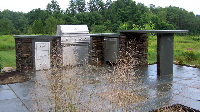 The Outdoor Kitchen with Seating Bar Is a Beautiful Space for Cooking and Eating
